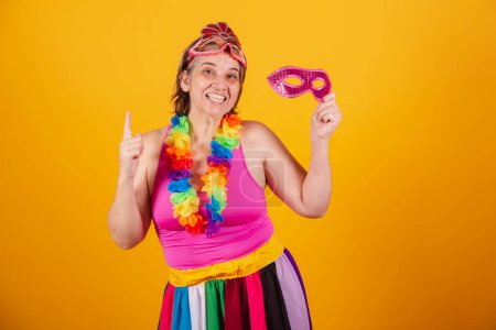 Téléchargez les photos : Femme adulte en vêtements de carnaval souriant à la caméra avec un masque de carnaval. danse - en image libre de droit