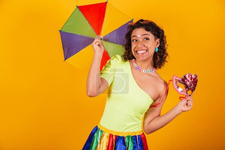 Foto de Hermosa mujer brasileña afroamericana, en ropa de carnaval, animando, usando sombrilla de colores. y máscara de carnaval. - Imagen libre de derechos