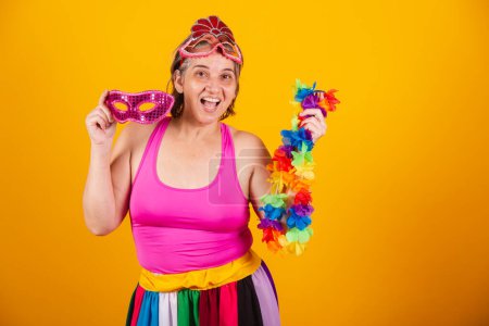 Téléchargez les photos : Femme adulte en vêtements de carnaval, souriant à la caméra, tenant collier de fleurs et masque. - en image libre de droit