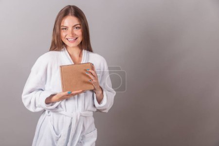 Photo for Brazilian blonde woman showing wonderful hair. dressed in a robe. holding small cardboard boxes with cosmetics. - Royalty Free Image