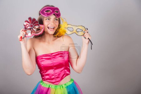 Téléchargez les photos : Femme blonde brésilienne vêtue de vêtements de carnaval rose. masques de carnaval tenant. - en image libre de droit