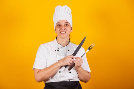 Photo for Adult Brazilian woman, chef, master in gastronomy. Cook. holding barbecue knife and fork. - Royalty Free Image