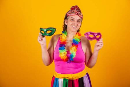 Téléchargez les photos : Femme adulte en vêtements de carnaval, souriant à la caméra avec des masques de carnaval tenant. - en image libre de droit