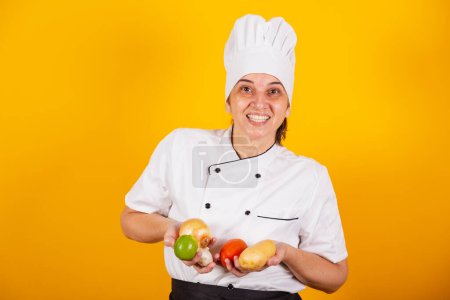 Photo for Adult Brazilian woman, chef, master in gastronomy. holding various plant foods and vegetables. - Royalty Free Image