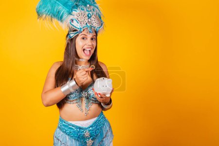 Téléchargez les photos : Belle femme brésilienne avec des vêtements de carnaval bleu, couronne de plumes, reine du carnaval, tenant tirelire et pièce de monnaie. - en image libre de droit