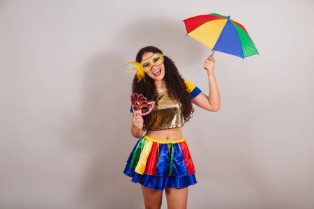 Téléchargez les photos : Jeune adolescente, brésilienne, avec des vêtements frevo, carnaval. tenant masque frevo et parapluie. - en image libre de droit