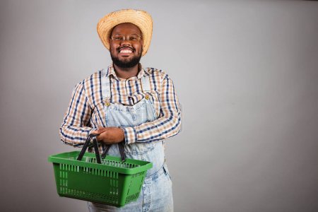 Photo for Brazilian black man wearing country clothes from festa junina,festa de so joo. arrai, holding market basket, shopping, promotions. - Royalty Free Image
