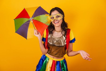 Photo for Beautiful brazilian woman in carnival clothes, with frevo clothes, and colorful umbrella and mask. welcome. - Royalty Free Image