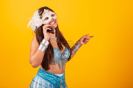 Téléchargez les photos : Belle femme brésilienne en bleu et blanc vêtements de carnaval. tenant smartphone sur appel vocal. - en image libre de droit