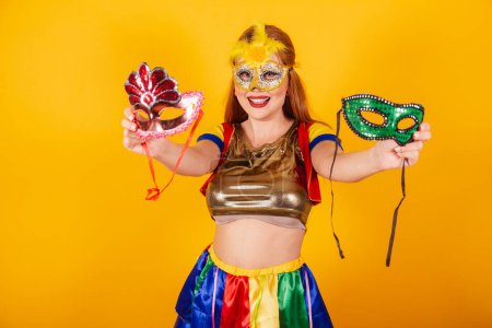 Téléchargez les photos : Rousse brésilienne, avec des vêtements de carnaval, frevo, et parasol coloré. portant un mascara et tenant des masques. - en image libre de droit