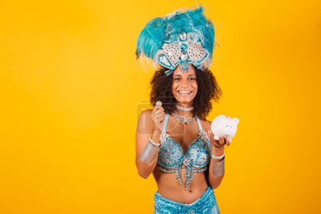 Photo for Black woman queen of Brazilian samba school, with blue carnival clothes and crown of feathers. holding mask. holding piggy bank and coin - Royalty Free Image