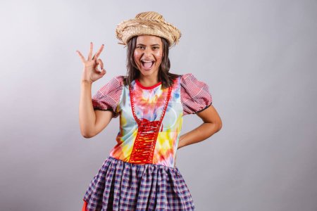 Téléchargez les photos : Femme brésilienne vêtue de vêtements de campagne, fête So Joo, fête Junina. ok signe avec les doigts. - en image libre de droit