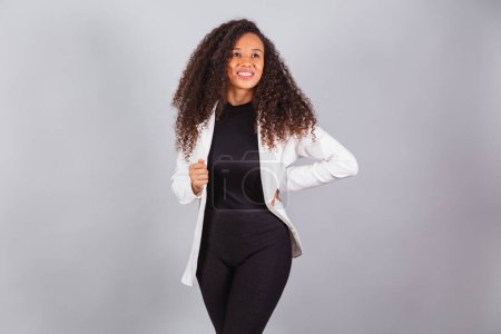 Foto de Foto horizontal, hermosa mujer brasileña negra, mujer de negocios, vestido de traje blanco, sonriente, optimista. - Imagen libre de derechos