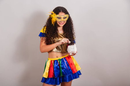 Téléchargez les photos : Jeune adolescente, brésilienne, avec des vêtements frevo, carnaval. tenant tirelire et pièce. - en image libre de droit