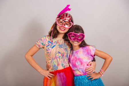 Photo for Two Brazilian children, girls, dressed in carnival clothes, hugging and smiling at the camera. - Royalty Free Image