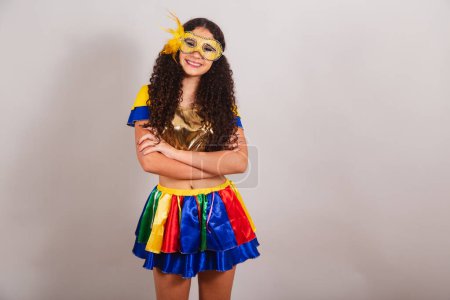 Téléchargez les photos : Jeune adolescente, brésilienne, avec des vêtements frevo, carnaval. masque, bras croisés. - en image libre de droit