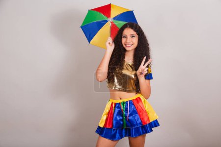 Foto de Jovencita adolescente, brasileña, con ropa frevo, carnaval. con paraguas signo de paz y amor. - Imagen libre de derechos