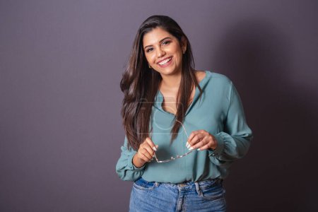Photo for Horizontal photo. Beautiful Brazilian woman, with casual clothes, Jeans and green shirt. holding glasses. - Royalty Free Image