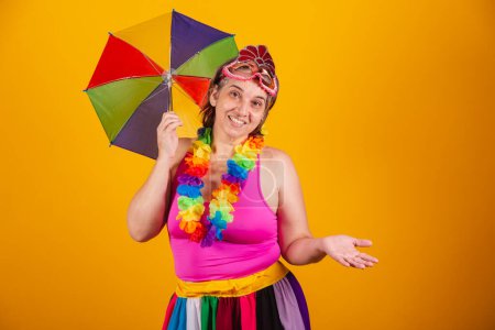 Photo for Adult woman in carnival clothes, smiling at camera with holding colorful parasol. saying welcome. - Royalty Free Image