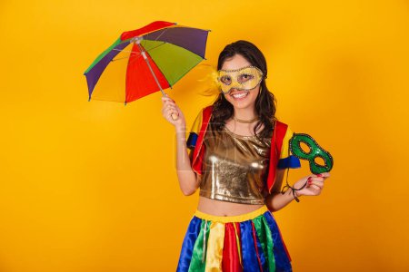 Photo for Beautiful brazilian woman in carnival clothes, with frevo clothes, and colorful umbrella and mask. smiling. - Royalty Free Image