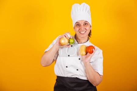 Photo for Adult Brazilian woman, chef, master in gastronomy. holding various plant foods and vegetables. - Royalty Free Image