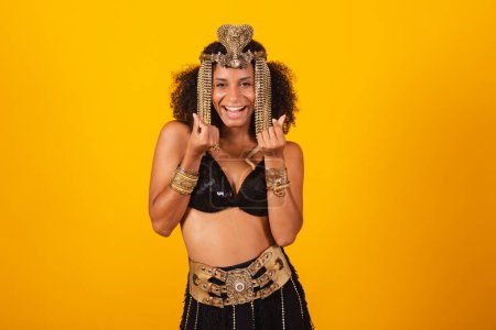 Foto de Hermosa mujer negra brasileña, en ropa de carnaval Cleopatra, haciendo corazón con los dedos. - Imagen libre de derechos