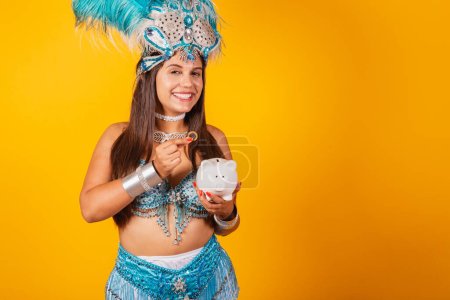 Téléchargez les photos : Belle femme brésilienne avec des vêtements de carnaval bleu, couronne de plumes, reine du carnaval, tenant tirelire et pièce de monnaie. - en image libre de droit