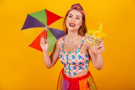 Téléchargez les photos : Rousse brésilienne, avec des vêtements de carnaval, avec parasol coloré et masque jaune. - en image libre de droit