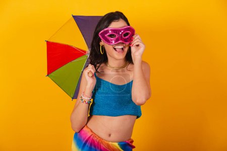 Téléchargez les photos : Belle femme brésilienne en vêtements de carnaval, tenant parapluie coloré et masque de carnaval. - en image libre de droit