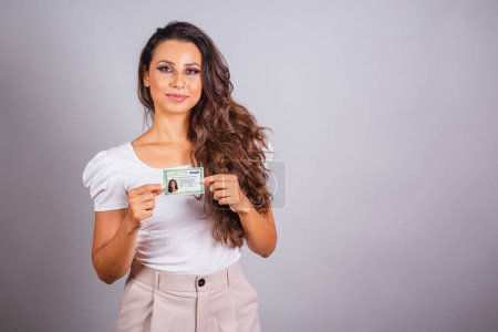 Photo for Brazilian woman, brown hair, holding identity card, RG, Brazilian document. - Royalty Free Image