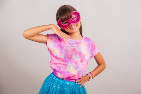 Téléchargez les photos : Belle fille brésilienne, enfant, habillée pour le carnaval au Brésil. avec masque de carnaval, pose pour photo. - en image libre de droit