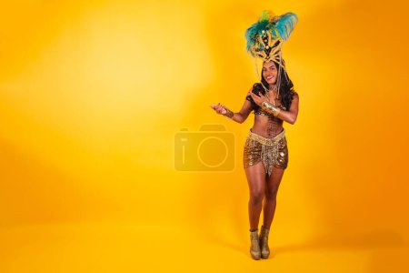 Téléchargez les photos : Photo horizontale, corps entier, femme brésilienne noire en vêtements de carnaval. montrer quelque chose à gauche. - en image libre de droit