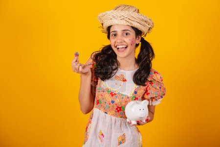 Beautiful Brazilian woman, with June party clothes, holding coin and piggy bank.