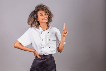 Téléchargez les photos : Jeune Brésilienne noire, cuisinière, chef cuisinière, portant l'uniforme de restaurant. avoir des idées. - en image libre de droit