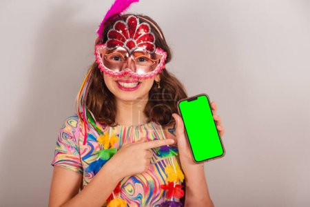 Foto de Niño brasileño, niña, vestido de carnaval. Mostrando Smartphone, pantalla croma verde. Mostrando teléfono celular, foto de cerca. - Imagen libre de derechos