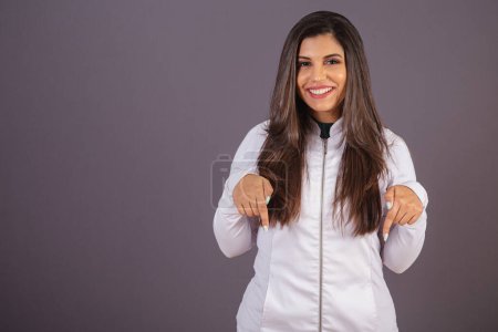 Photo for Horizontal photo. brazilian woman with medical coat, nutritionist. pointing to the center. - Royalty Free Image