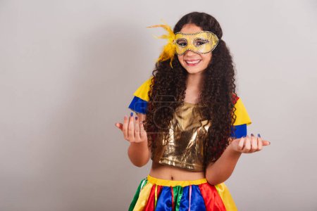 Téléchargez les photos : Jeune adolescente, brésilienne, avec des vêtements frevo, carnaval. masque, invitant avec les mains. - en image libre de droit