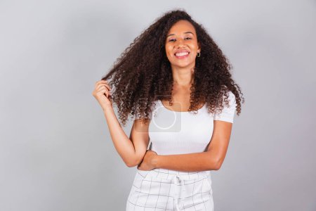Photo for Horizontal photo, beautiful black Brazilian woman, dressed in white, casual clothes, smiling. - Royalty Free Image