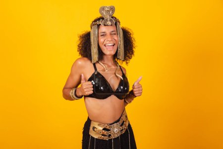 Téléchargez les photos : Belle femme brésilienne noire, en vêtements de carnaval Cleopatra, pouce levé, positive - en image libre de droit