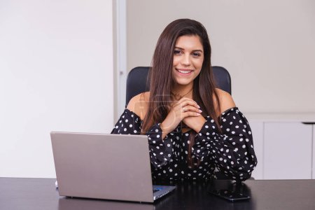 Foto de Hermosa mujer brasileña, emprendedora, en la oficina, usando notebook y smartphone, trabajando. - Imagen libre de derechos
