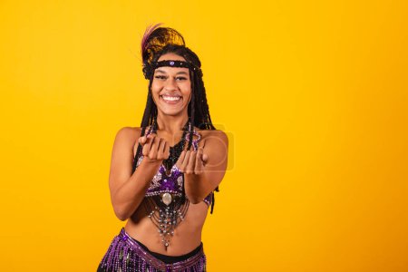 Photo for Beautiful black Brazilian woman, in purple carnival clothes, inviting with hands. - Royalty Free Image