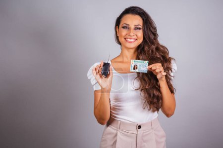 Photo for Brazilian woman, brown hair, holding driver's license, Brazilian document and car key, new car. - Royalty Free Image