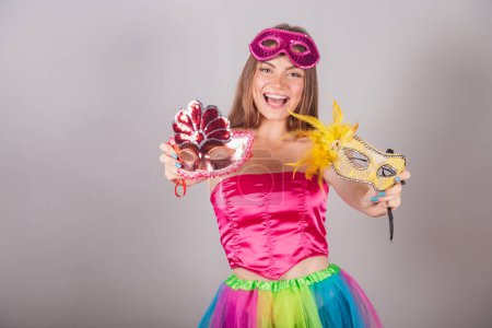 Photo for Brazilian blonde woman dressed in pink carnival clothes. holding carnival masks. - Royalty Free Image