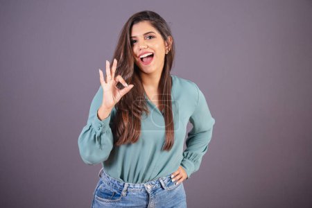 Photo for Horizontal photo. Beautiful Brazilian woman, with casual clothes, Jeans and green shirt. ok sign, all right. - Royalty Free Image
