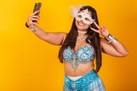Foto de Hermosa mujer brasileña en ropa de carnaval azul y blanco. sosteniendo smartphone tomando autorretrato. - Imagen libre de derechos