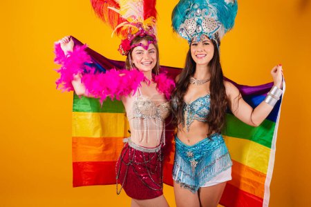 Photo for Two female brazilian female friends, wearing carnival outfits, holding lgb flag - Royalty Free Image