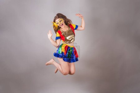 Foto de Mujer rubia brasileña, vestida con ropa frevo, máscara de carnaval, saltando. - Imagen libre de derechos