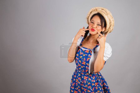 Photo for Brazilian woman, northeastern, with June party clothes, straw hat. sending kiss, showing mouth, kiss booth. - Royalty Free Image