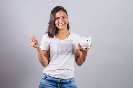 Téléchargez les photos : Femme brésilienne avec tirelire et monnaie. finances, épargne. investissement. - en image libre de droit