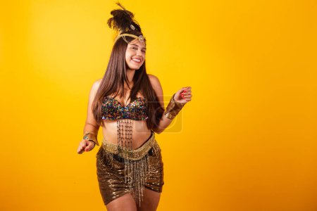 Foto de Hermosa mujer brasileña vestida con ropa dorada de carnaval, bailando, disfrutando y festejando. - Imagen libre de derechos